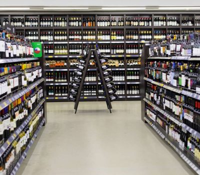 Moscow, Russia - November 17, 2019: Decoration with a wooden triangular counter and bottles of red wine in a supermarket. Wine store, bottles with alcoholic grape white wine on the shelves