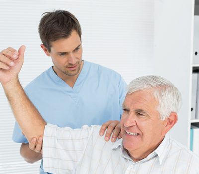 Male physiotherapist assisting senior man to stretch his hand in