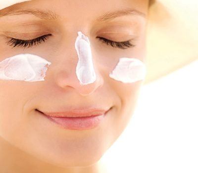 Portrait of a young woman with sun cream on face, eyes closed