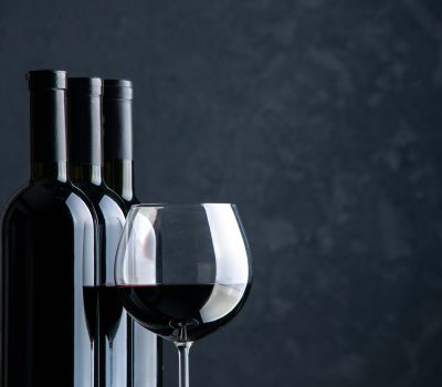 front-view-bottles-wine-with-glass-wine-dark-surface